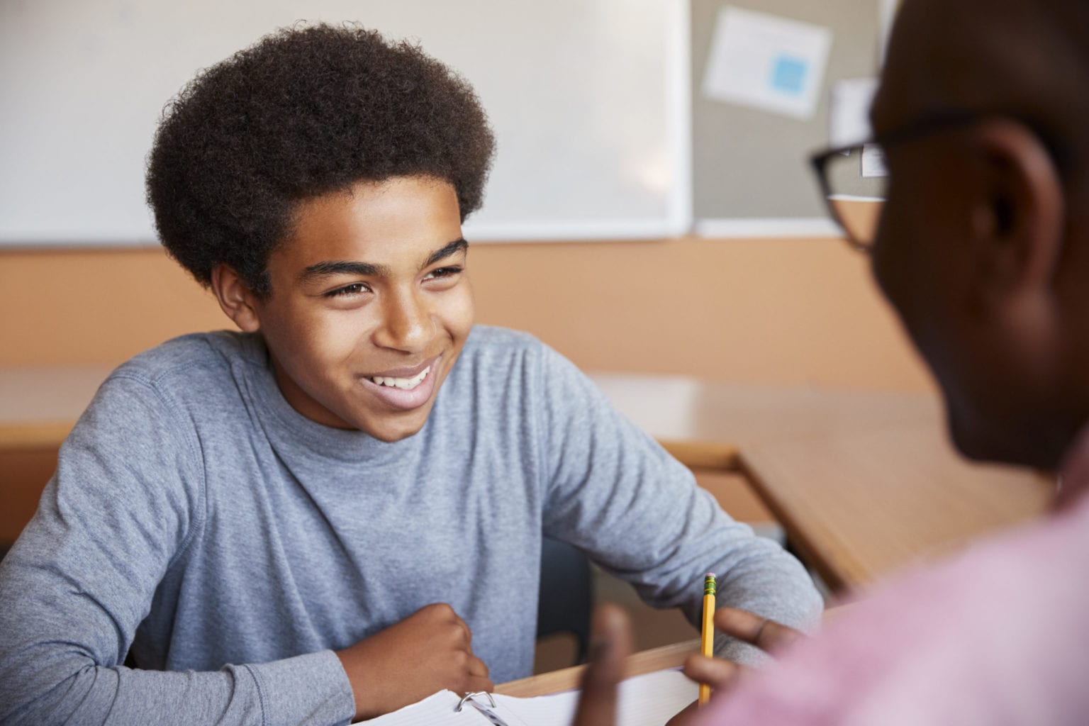 High School Tutor Giving Male Student One To One Tuition At Desk